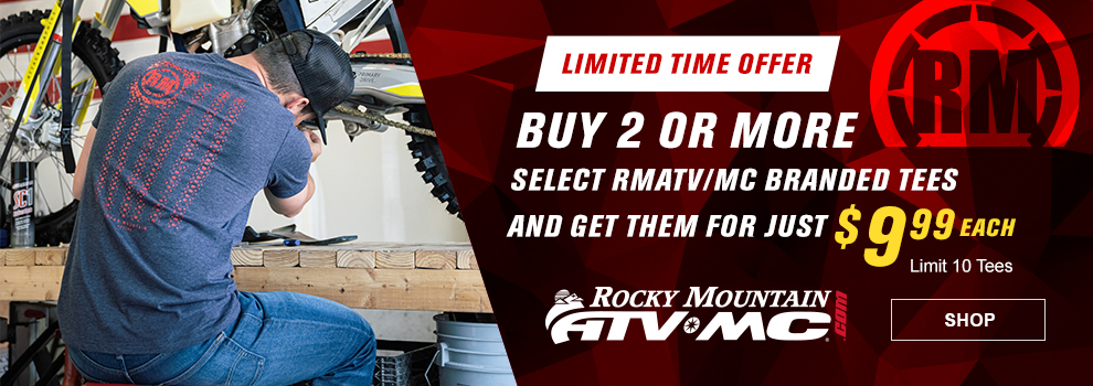 Rocky Mountain ATV/MC, Limited Time Offer, Buy 2 or more select RMATV/MC branded tees and get them for just $9 and 99 cents each, Limit 10 tees, a man working on a Husqvarna dirt bike wearing the navy heather American Grit t-shirt, link, shop